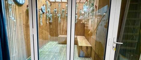 Une pièce dotée d’une porte-fenêtre coulissante donnant sur un espace extérieur avec une terrasse en bois et un banc.