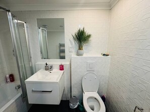 A bathroom with a shower, sink, toilet, and a small potted plant. - Spacious apartment with private patio (Greater London)