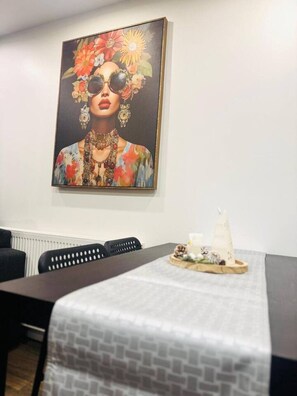 A dining area with a table set for two, a painting on the wall, and a decorative centerpiece on the table. - Spacious apartment with private patio (Greater London)