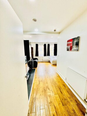 A hallway with wooden flooring, a radiator, and a wall-mounted picture. - Cosy one bedroom flat near Aldgate East station (Greater London)