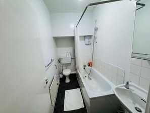 Ein kleines, kompaktes Badezimmer mit Toilette, Badewanne und Waschbecken.