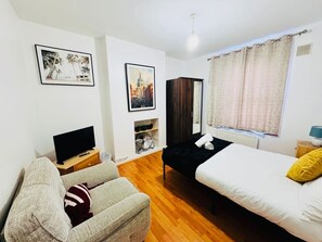 Ein Schlafzimmer mit einem Bett, einer Couch, einem Fernseher und Kunstwerken an den Wänden.
