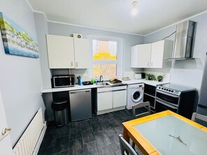 Eine kompakte Küche mit Geschirrspüler, Waschmaschine, Mikrowelle und Backofen.