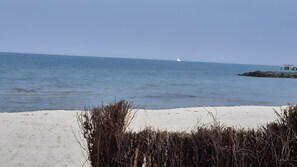 A beach with white sand, calm water, and a distant ship. - Apartment at Schönberger Strand – Just 200 Meters from the Beach (Schönberg)