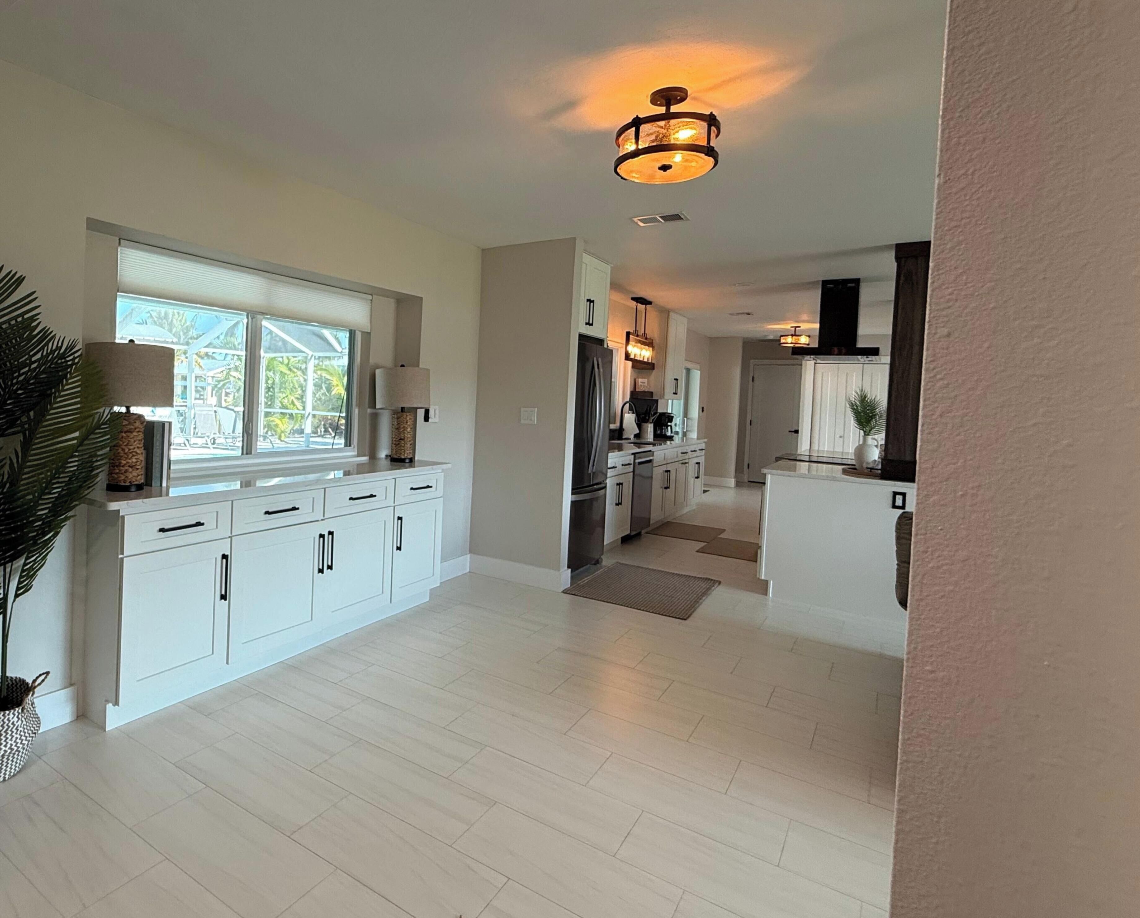 A modern kitchen with white cabinetry, a built-in oven, and a central island.