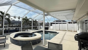 An outdoor pool area with a hot tub, covered seating, and a barbecue grill. - A 2B/2B Hidden Waterfront Gem in St James City! (St James City)