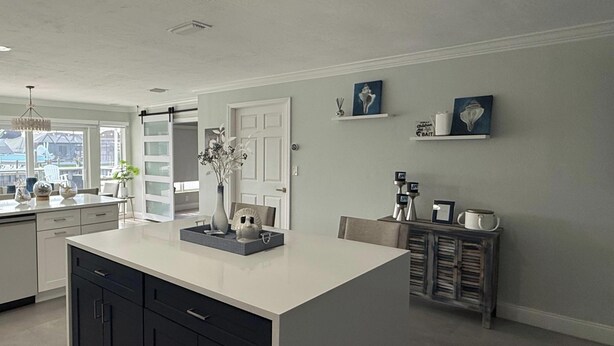 A modern kitchen with a large island, dark cabinets, and a view of the outside. - A 2B/2B Hidden Waterfront Gem in St James City! (St James City)