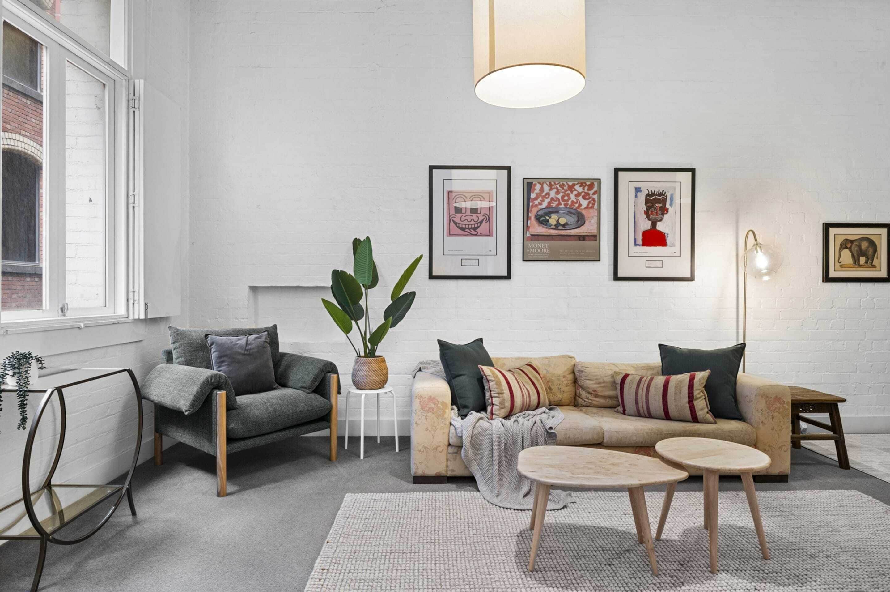 Ein modernes Wohnzimmer mit einer Couch, einem Sessel, einem Couchtisch und einem Blumentopf.