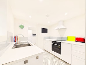 Una cocina moderna con un lavamanos, estufa, microondas y un reloj en la pared.