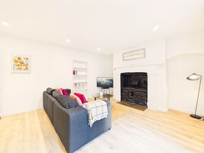 Ein modernes Wohnzimmer mit Kamin, Sofa, Fernseher und Bücherregal.