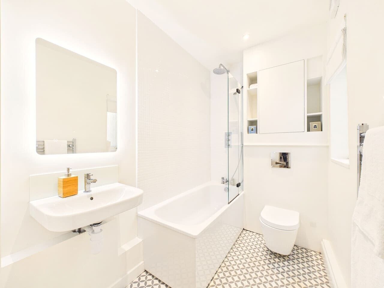 A modern bathroom with a white sink, a bathtub, a toilet, and a glass-enclosed shower.