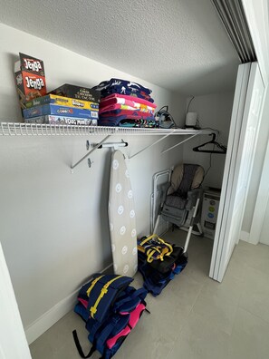 Ein Stauraum mit Regalen, auf denen Brettspiele, ein Kleidungsstück und ein Kinderwagen stehen.