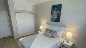 A bedroom with a bed, two bedside tables with lamps, a ceiling fan, a wall-mounted artwork, and a wardrobe. - The Gulf Oasis-
 Pool, hot tub, boat ramp, floating dock, kayaks, waterfront (Hudson)