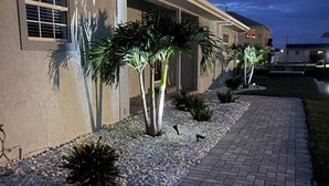 A residential building with a paved walkway, palm trees, and a clear sky. - The Gulf Oasis-
 Pool, hot tub, boat ramp, floating dock, kayaks, waterfront (Hudson)