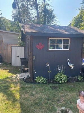A small shed with a window, a red maple leaf decoration, and a bird sculpture. - Siesta Pines Peaceful Retreat (Waubaushene)