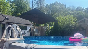 En pool som står ovan jord, med en stege, en täckt uteplats och uppblåsbara leksaker.
