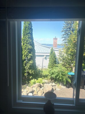 A window with a view of a building, trees, and a clear sky. - Siesta Pines Peaceful Retreat (Waubaushene)