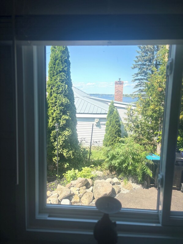 A window with a view of a building, trees, and a clear sky. - Siesta Pines Peaceful Retreat (Waubaushene)