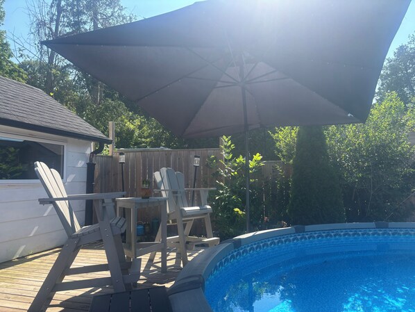 A wooden deck with a pool, outdoor furniture, and a large umbrella. - Siesta Pines Peaceful Retreat (Waubaushene)