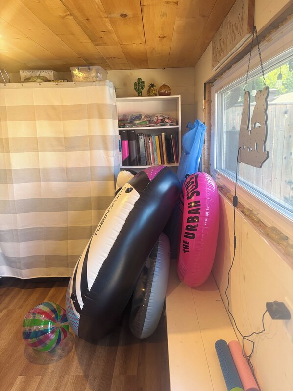 A room with a wooden ceiling, a window with a decorative cutout, a shelf with books and a cactus, and exercise equipment. - Siesta Pines Peaceful Retreat (Waubaushene)