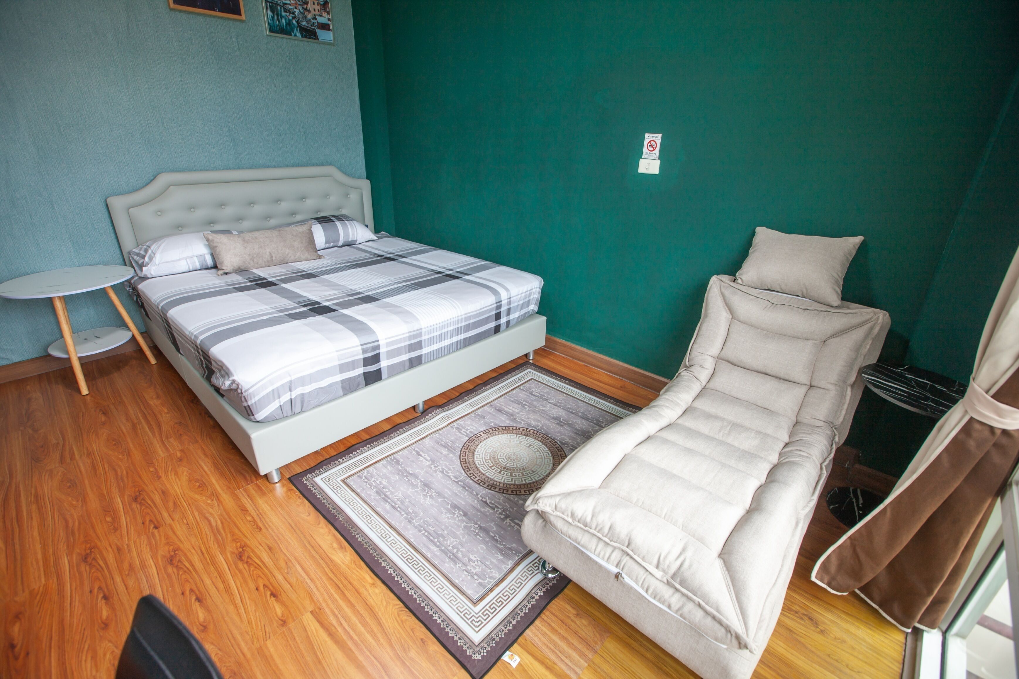A bedroom with a bed, a sofa, a small round table, and a rug.