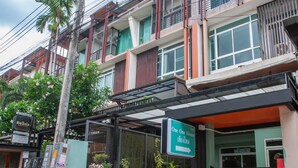 Un edificio de varios pisos con fachada verde y blanca, un letrero que indica 'One One House' y una entrada con portones.