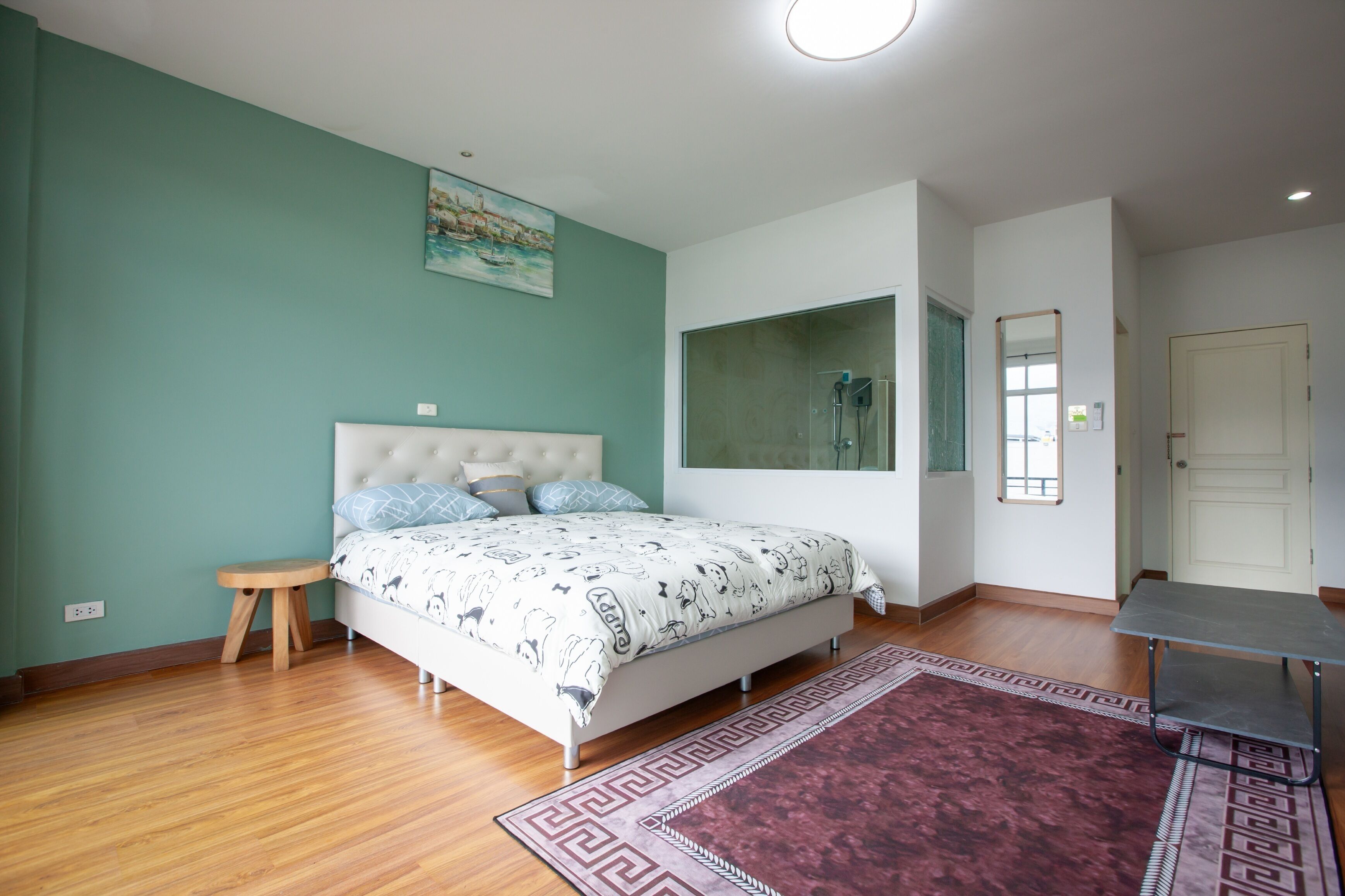 Une chambre à coucher avec un lit, un petit tabouret, un miroir et une porte.