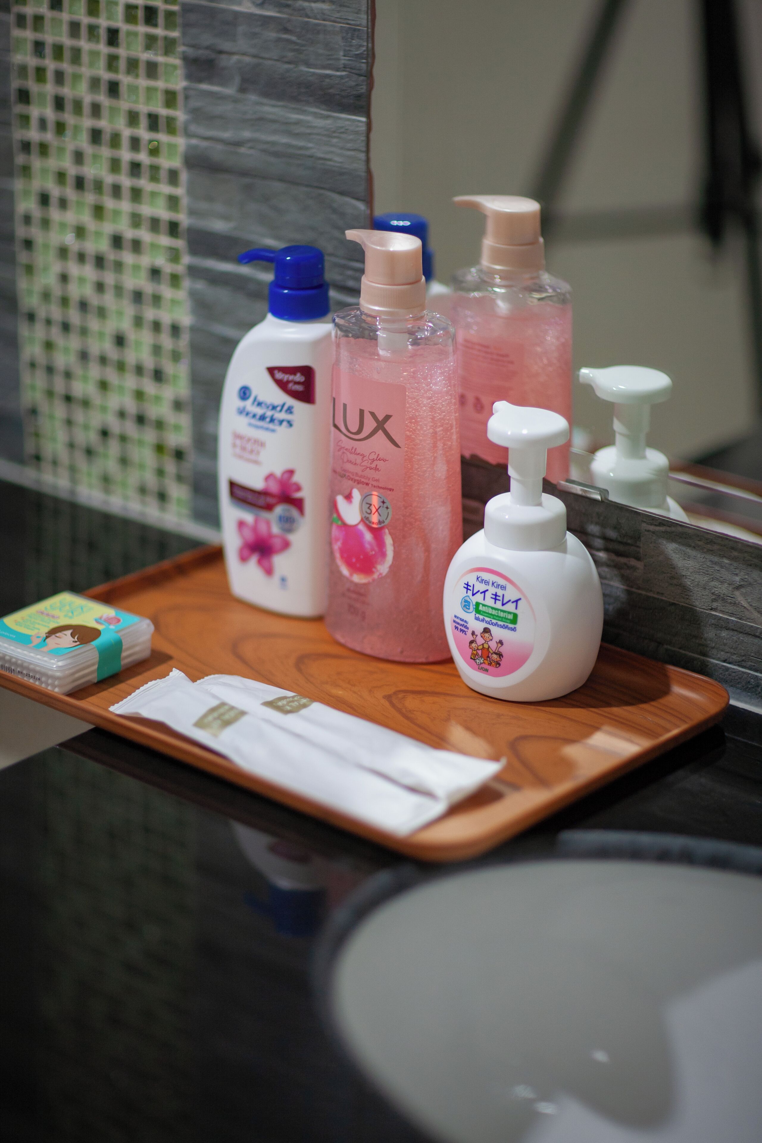 A tray with toiletries including a bottle of LUX soap, a bottle of Myher's lotion, and a bottle of Kirin Kira lotion.