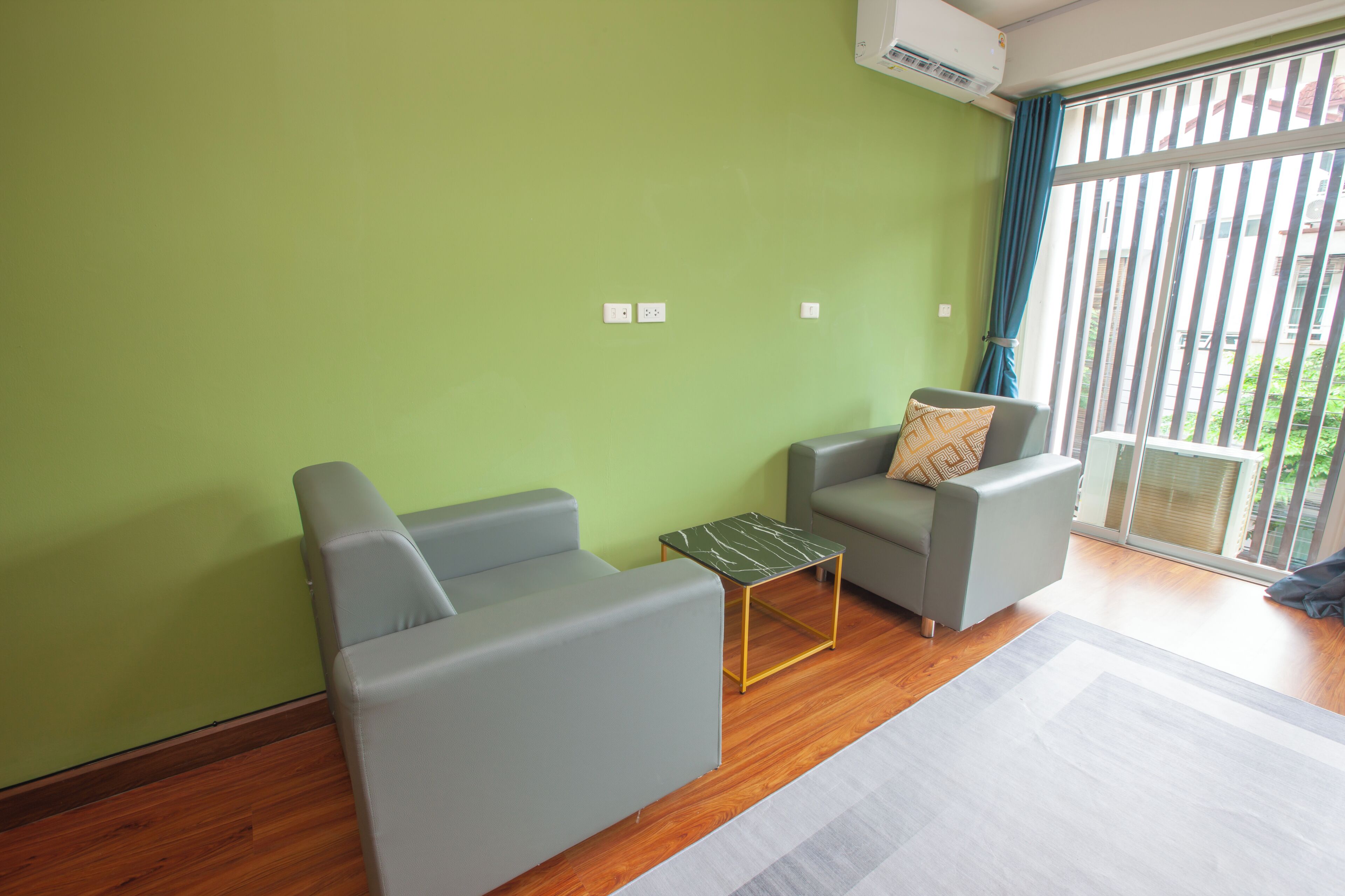 A room with two grey sofas, a small table, and a large window with curtains.
