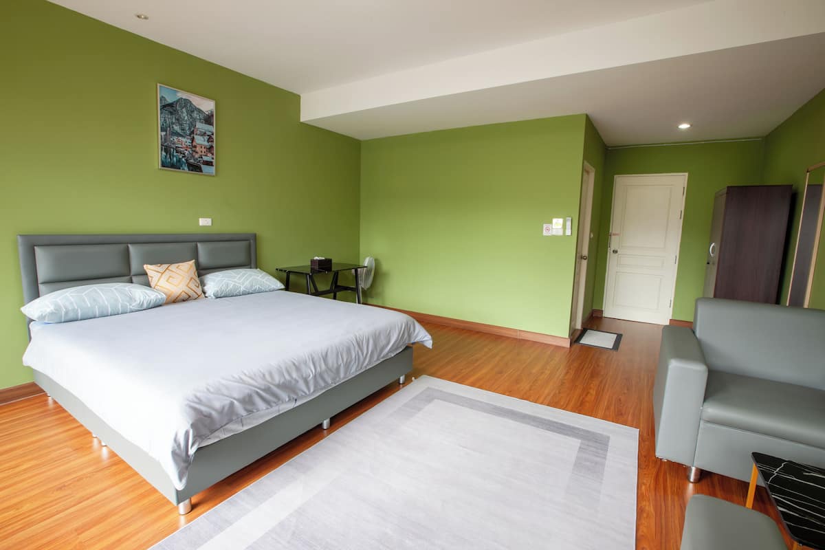 A bedroom with a bed, a small table, a chair, and a sofa.