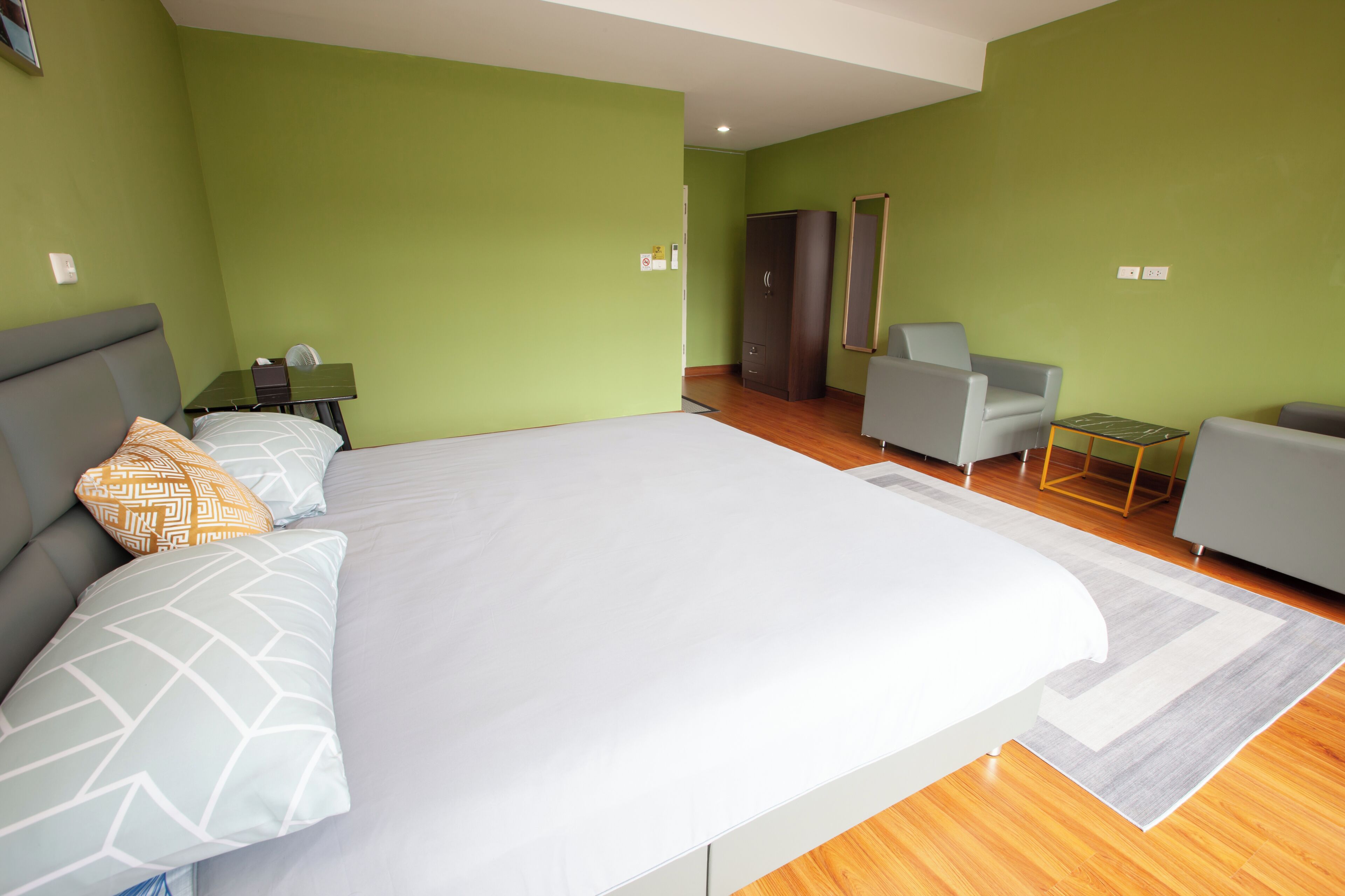 A bedroom with a large bed, a desk, a chair, and a wardrobe.