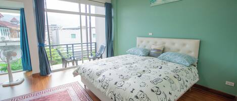 A bedroom with a large bed, a balcony with a view, and a painting on the wall.