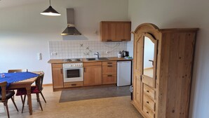 Eine kompakte Küche mit Holzausstattung, einem Einbauofen, einer Spüle und einem Essbereich mit Tisch und Stühlen.