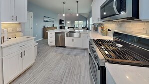 A modern kitchen with white cabinets, stainless steel appliances, and pendant lighting. - Lone Star Lookout | Pet-Friendly + Community Pool! (Rockport)