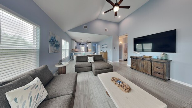 A spacious living room with a gray sectional sofa, a coffee table, and a TV mounted on the wall. - Lone Star Lookout | Pet-Friendly + Community Pool! (Rockport)