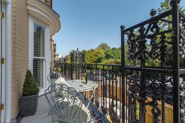A balcony with a wrought iron railing, a small table with chairs, and a potted plant. - Host & Stay | Kings Cloisters (York)