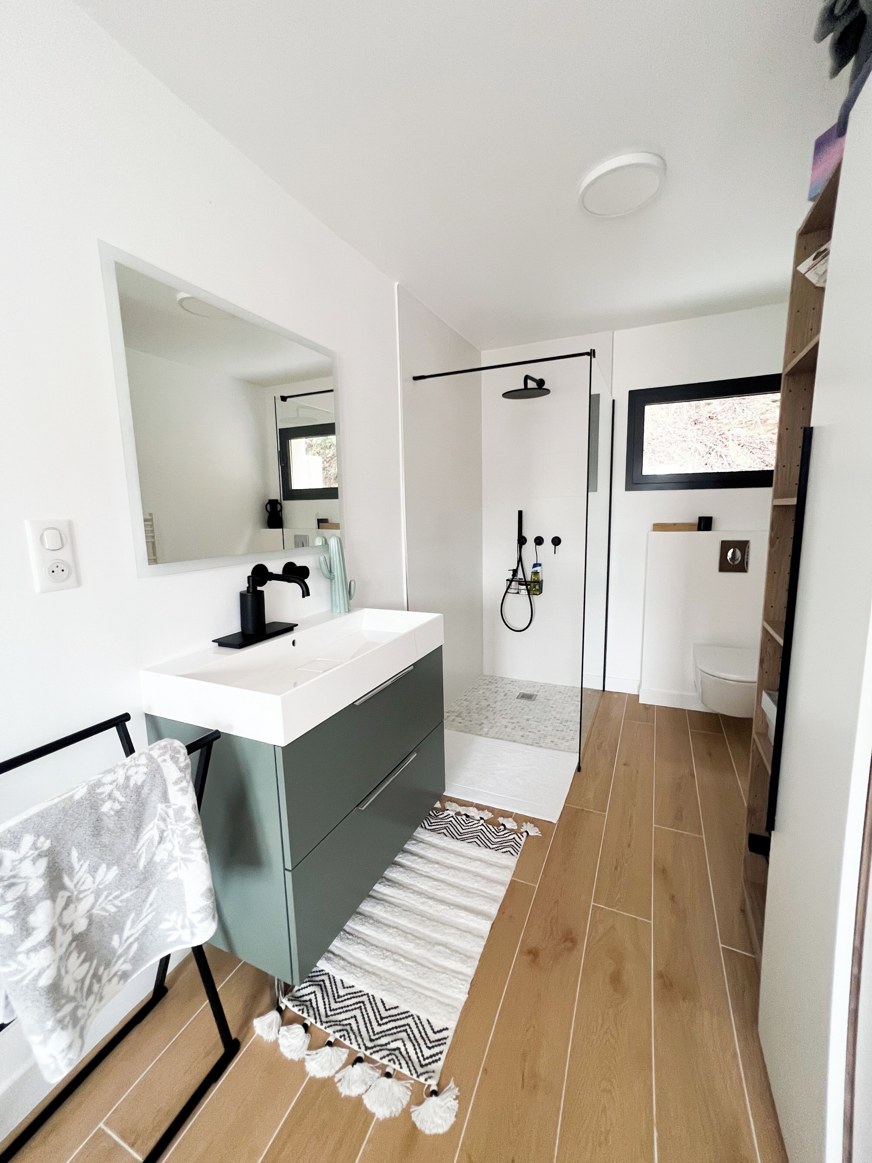 A modern bathroom with a white sink, dark grey cabinet, and a shower area.