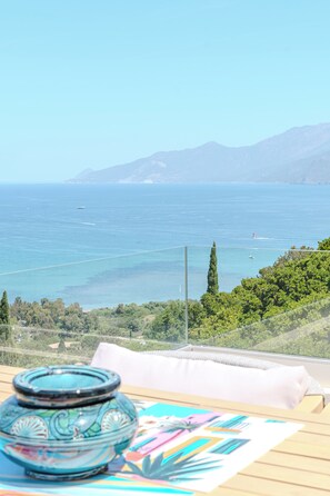 A balcony with a view of the sea, a glass vase, and a colorful mat. - VILLA prestige ROYA vue mer à Saint Florent (Saint-Florent)