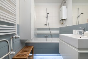 Une salle de bain moderne équipée d’une baignoire, d’une douche et d’un lavabo avec des articles de toilette.