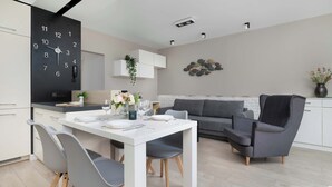 Eine moderne Küche mit einer schwarzen Uhr, weißen Schränken und einem grauen Sofa.