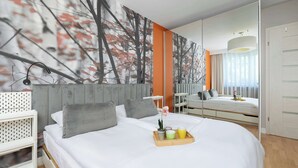 Ein modernes Schlafzimmer mit einem großen Bett, einem Nachttisch, einem Spiegel und einem Wandbild.