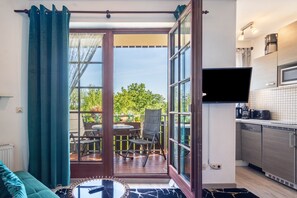 A modern kitchen with a flat-screen TV, a dining area with a table and chairs, and a view of greenery outside. - Holiday Apartment in the Harz 2 (Bad Sachsa)