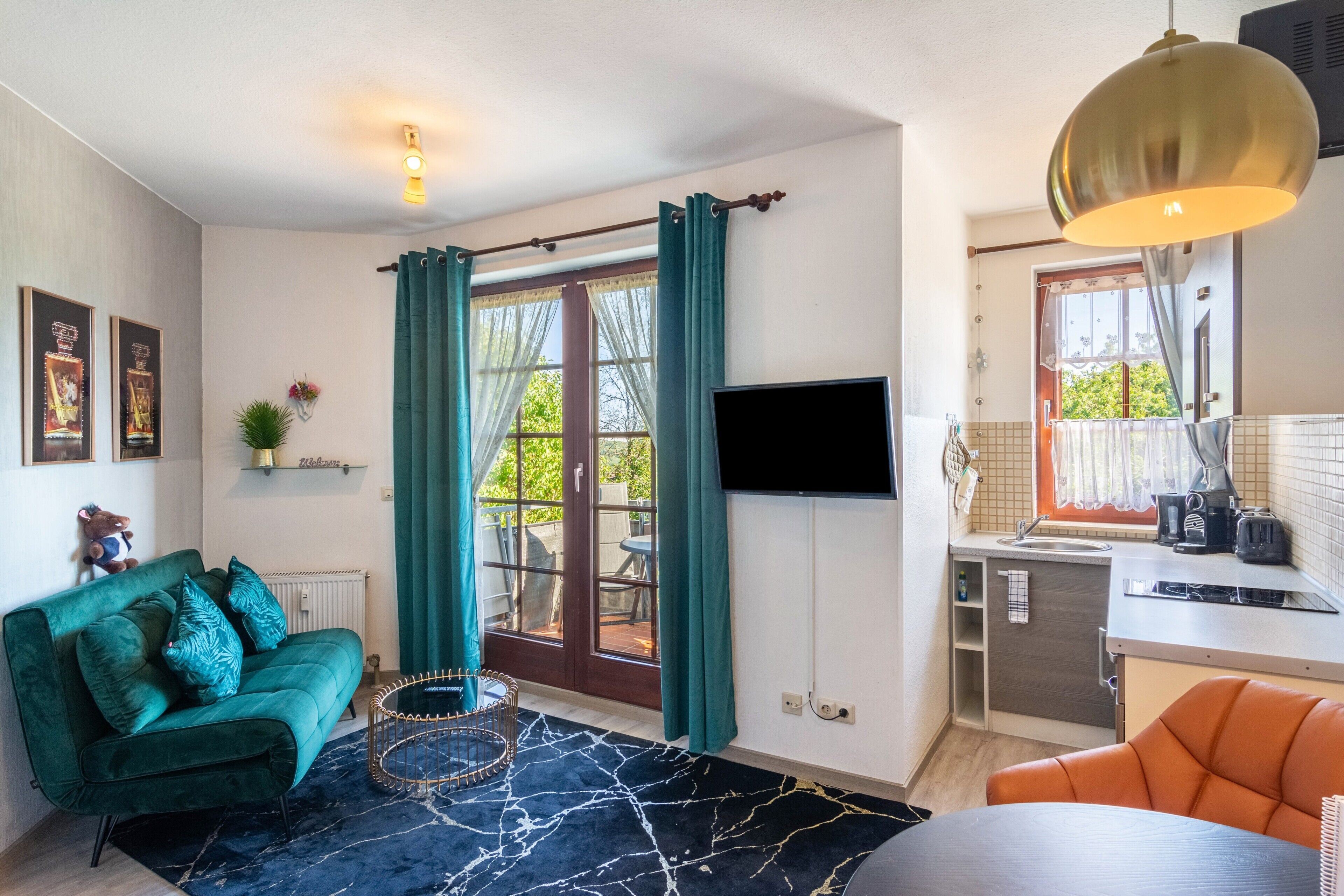 A compact living space with a sofa, a dining table, a kitchen area, and a television.