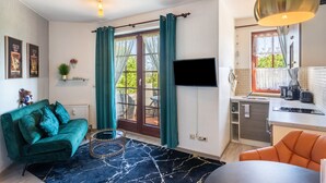 Un espacio habitable compacto con sofá, una mesa de comedor, una zona de cocina y televisión.