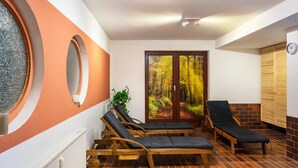 Una habitación con dos sillones de madera, una planta en maceta y vistas a un bosque a través de un ventanal.