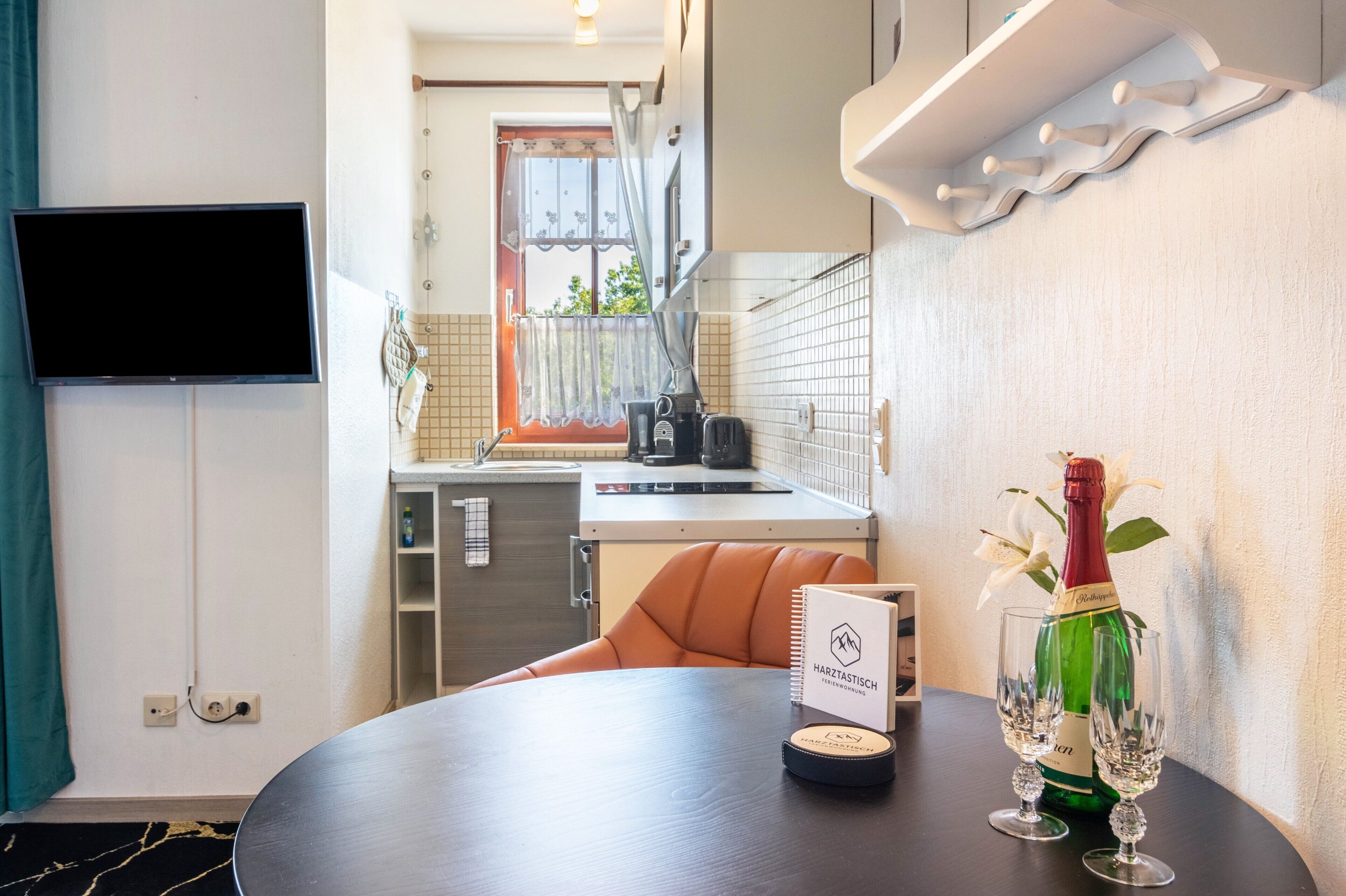 A hotel room with a dining table, a bottle of champagne, and a menu.