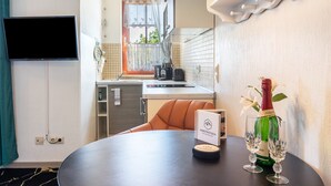 Habitación de hotel con una mesa de comedor, una botella de champán y un menú.