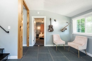 Ein Flur mit einer Treppe, ein Bett im angrenzenden Zimmer und zwei Stühle.