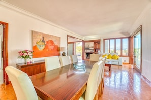 A spacious dining area with a long wooden table, several chairs, and a large painting on the wall. - House with pool Can Quiros Can Picafort (Can Picafort)