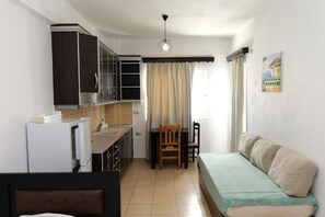A compact room with a kitchenette, a dining area, and a bed. - Fenix ApartHotel (Sarande)